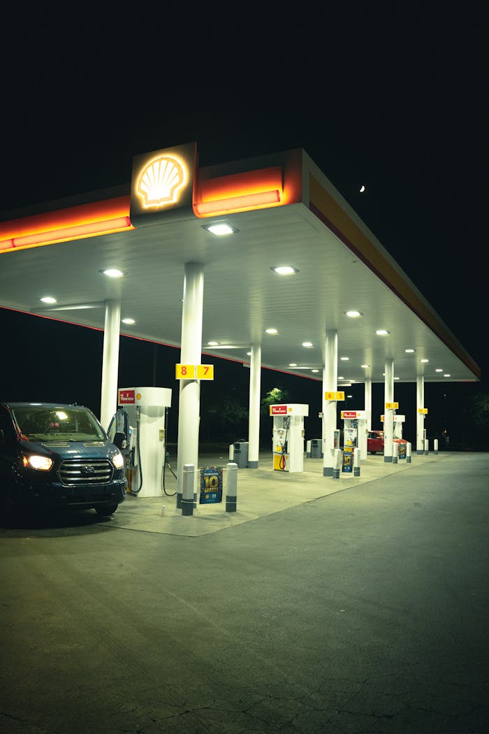 services-04 A gas station brightly lit at night with a parked car under neon lights.