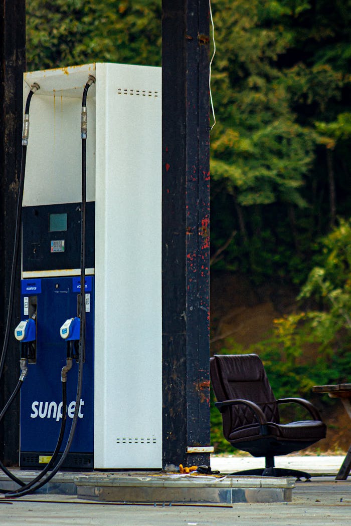 about-img A vintage gas pump with a rustic chair at an old station outdoors.