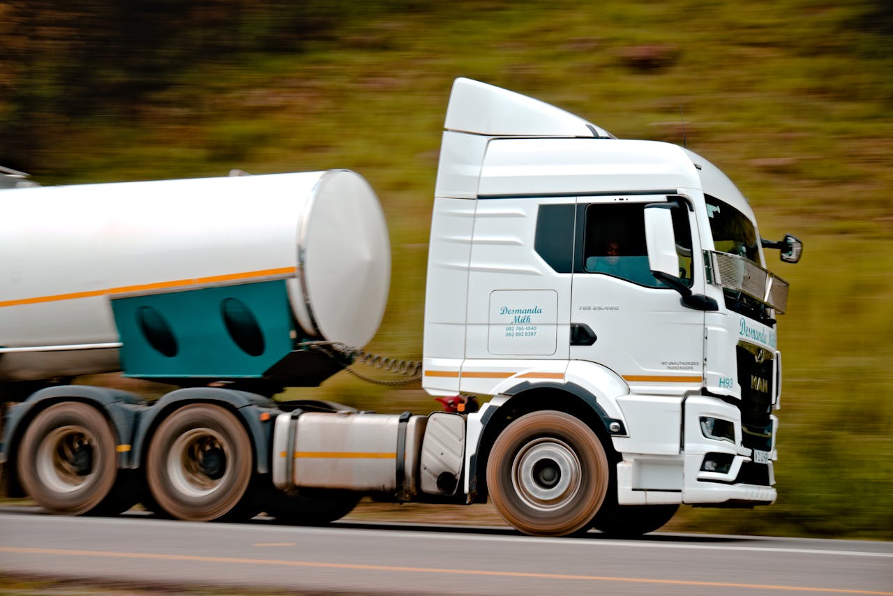 gallery-1 Close-up of a fast-moving white tanker truck on a highway, capturing motion and speed.