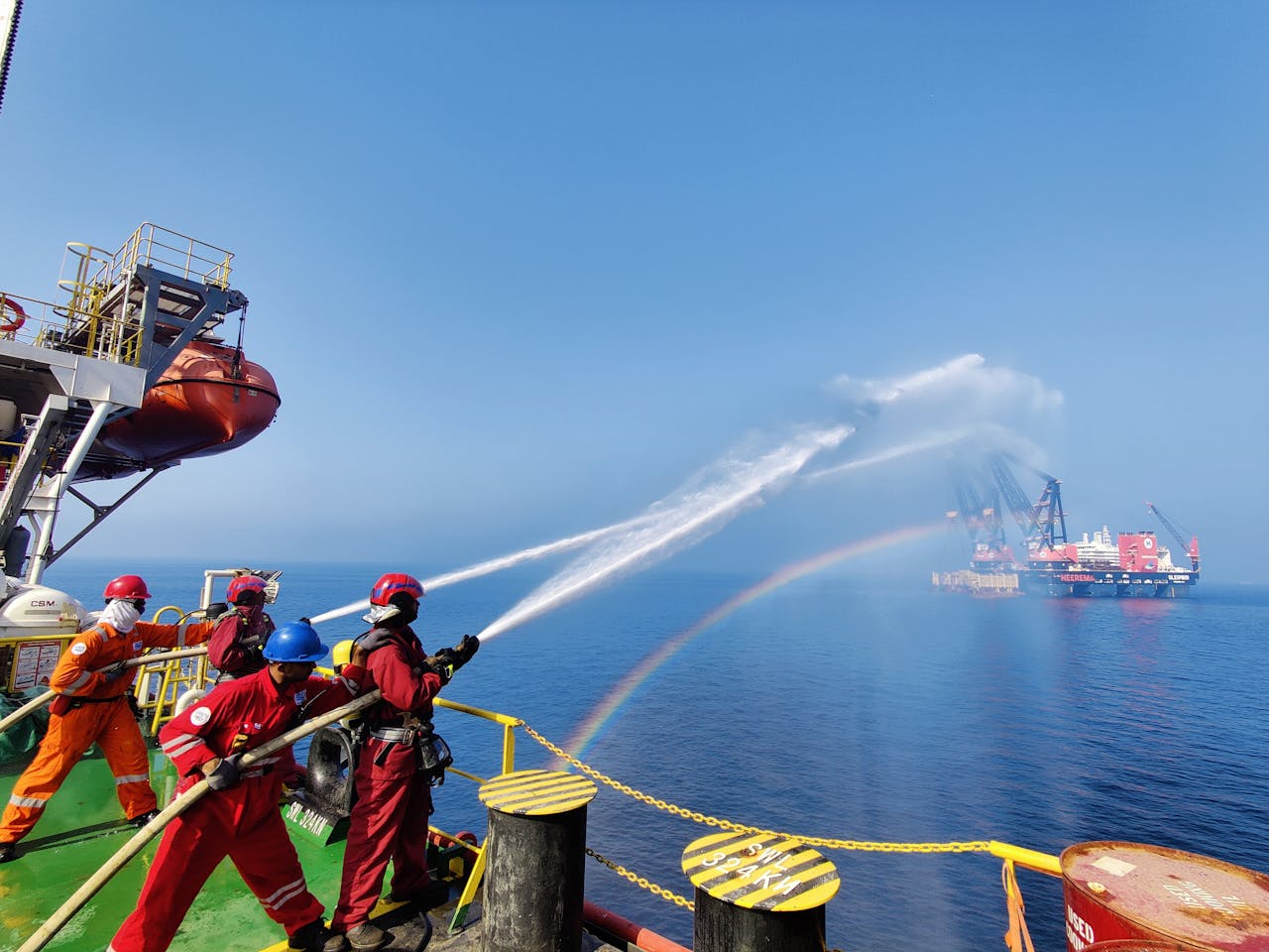 gallery-3 Workers on an offshore platform demonstrate teamwork using water hoses under a clear sky.