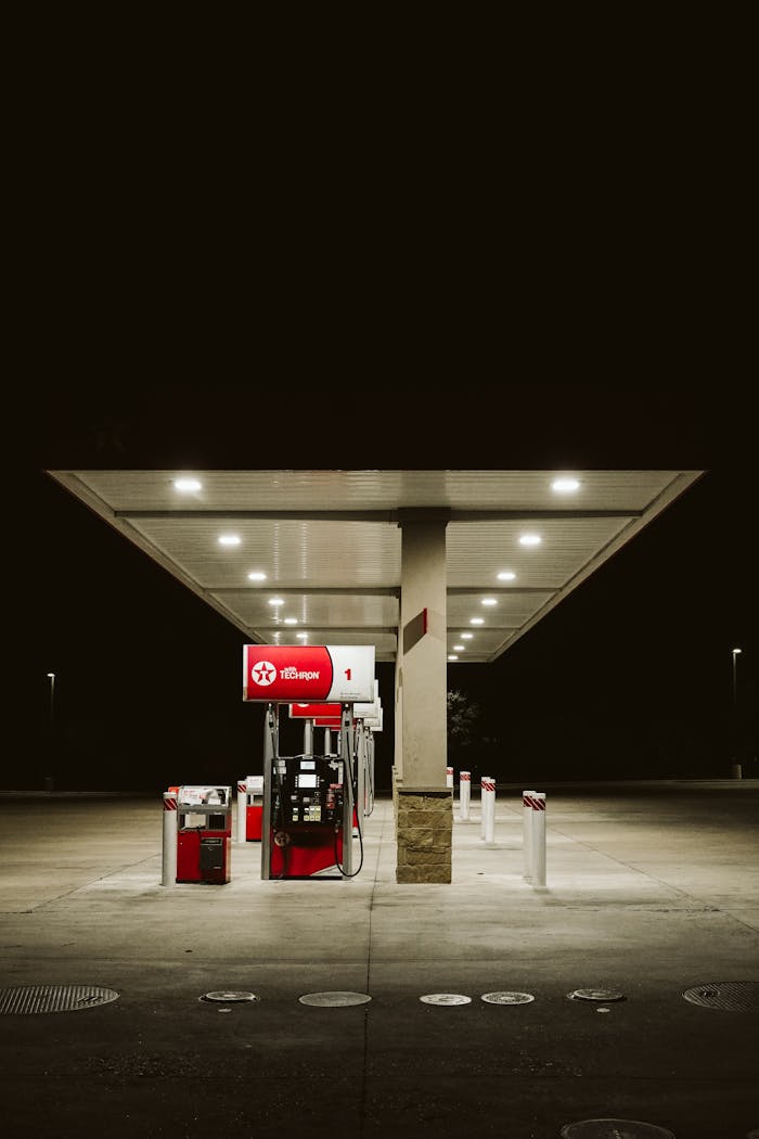 about-02 A dimly lit, empty gas station with a single illuminated pump at night.