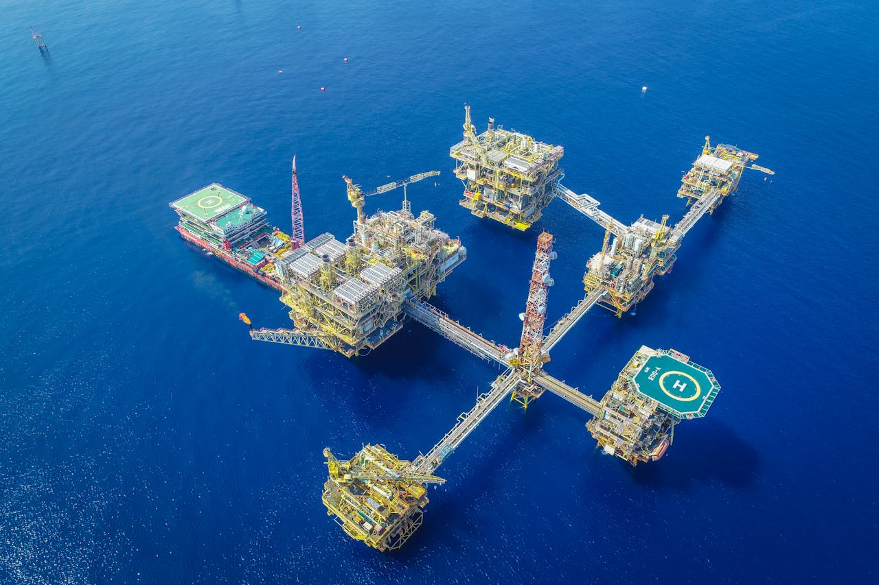 services-02 Drone shot of a large, complex offshore oil platform in deep blue ocean waters.